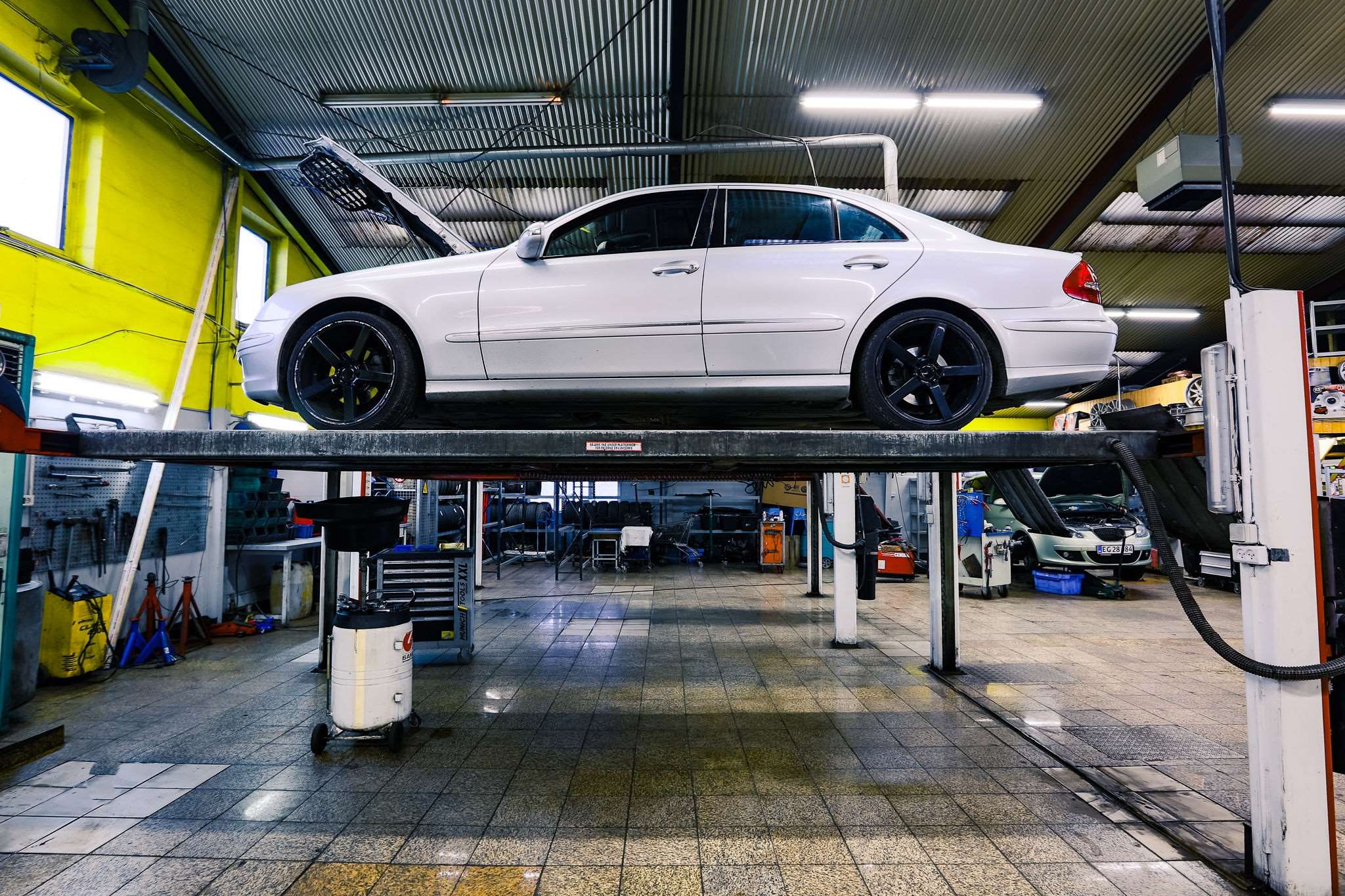 Hævet hvid bil indenfor hos autoværkstedet Apex Auto